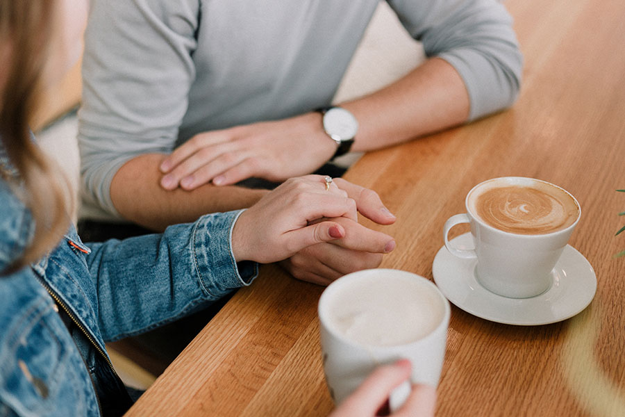Couple holding hands over coffee